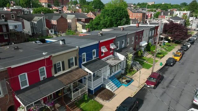 Colorful city homes on beautiful spring day. American infrastructure in large city. Aerial view of rowhouses lining street from angle.