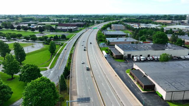 Drone view of cars traveling on large highway. Road system in America funded by tax payer dollars. Commuters drive on highway on spring day. Aerial view.