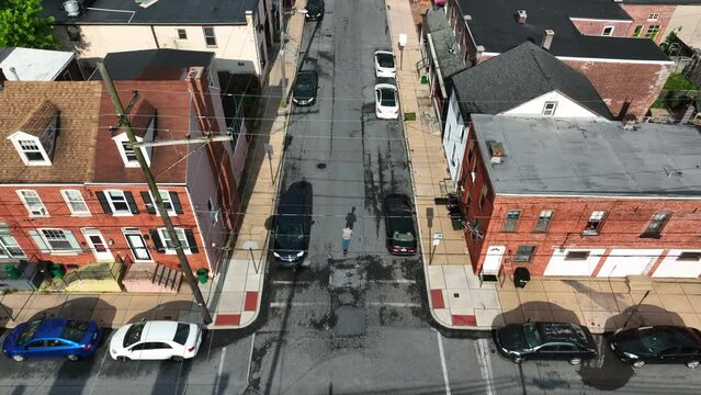 Aerial, top down tracking shot of man scooter in city. Electric scooter used as method of transportation on pleasant weather day in America.