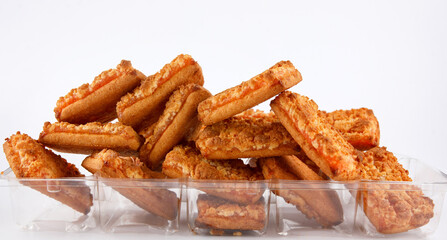 Orange cookies in a plastic container on a white background .