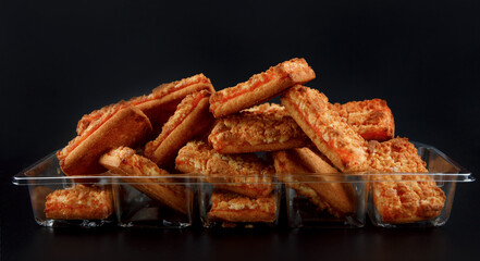 Orange cookies in a plastic container on a dark background .