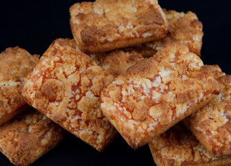 A bunch of orange cookies on a dark background .