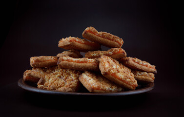 A plate of cookies with orange filling on a dark background .