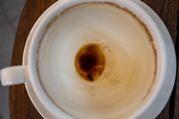 An empty coffee cup photographed from above with the rest of the coffee and coffee grounds on the bottom of the cup