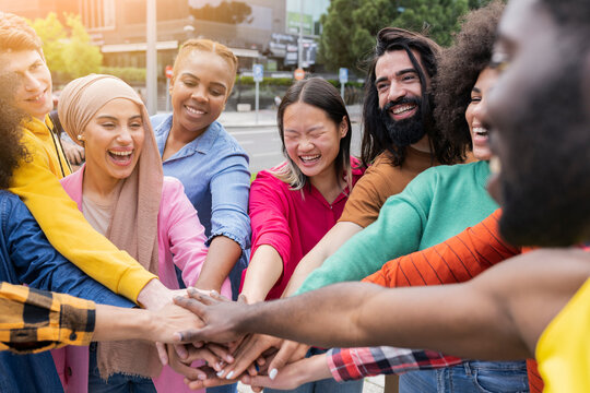 Group of young friends in the park come together in the center of a circle to give unity and strength to all - Millennials in a moment of team building - Multiracial youth