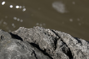 Close up of textured rocks against a high bokeh river.