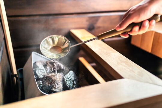 Sauna In Finnish Spa. Hot Steam, Water On Stones. Man In Wellness And Health Room In Finland. Warm Temperature Bath Therapy. Traditional Summer Cabin Relaxation.