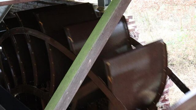 Close-up of metal paddles on a watermill wheel turning with circulating water, top perspective, Leumolen or Sint-Ursulamolen watermill Leubeek river, Nunhem in Midden-Limburg, the Netherlands