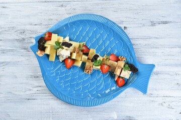 a set of cheeses on a skewer of parmesan cheese, dor blue, camembert with nuts and strawberries
