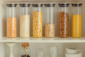 Kitchen shelf with cereals and pasta in glass jars. Organization of storage and order in the...