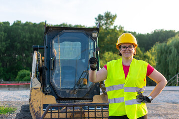 Cheerful female excavator operator on construction site. Woman construction apprentice learning to...