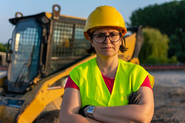Cheerful female excavator operator on construction site. Woman construction apprentice learning to...