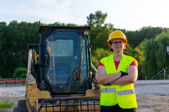 Cheerful female excavator operator on construction site. Woman construction apprentice learning to drive heavy equipment