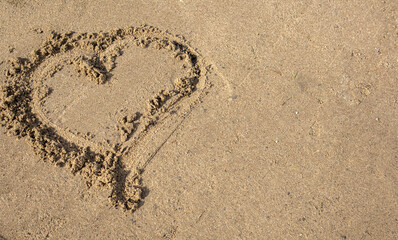 A heart drawn in the sand. Beach background. Top view, space for text