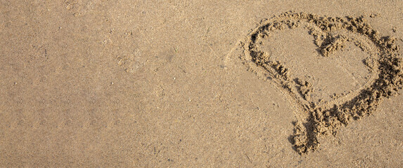 A heart drawn in the sand. Beach background. Top view, space for text
