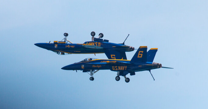Two Navy blue angel jets one upside down over the other