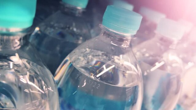 Mineral water in plastic bottles line up on the supermarket shelves or warehouse. Closeup shot. Dutch angle