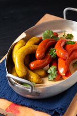 Food concept Assortment european homemade organic spicy sausage in aliminum tray on wooden board with black slate stone board with copy space