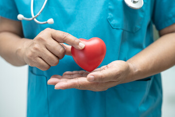 Doctor holding a red heart in hospital ward, healthy strong medical concept.
