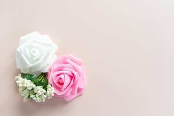 White and pink roses with white little flowers on a pale pink background with space for text