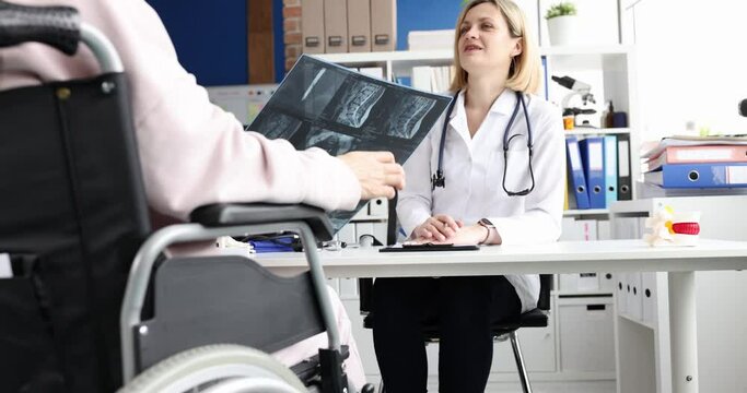 Radiologist examines a woman in wheelchair and x-rays spine
