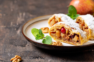 homemade fragrant strudel with apples and cinnamon on a plate on a wooden background with space for...