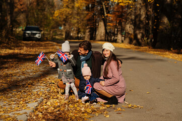 National holiday of United Kingdom. Family with british flags in autumn park.  Britishness...