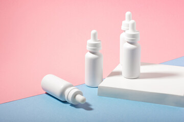 A set of white cosmetic bottles with a dropper, on a podium with hard shadows. The concept of face and body care at home and in a beauty salon