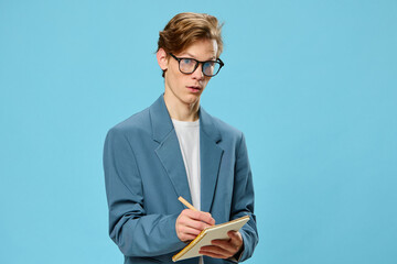 cute guy in glasses and a classic suit takes notes in a notebook