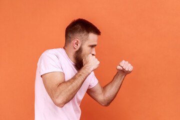 Side view of bearded man aggressive fighter holding clenched fists up ready to boxing, martial art...