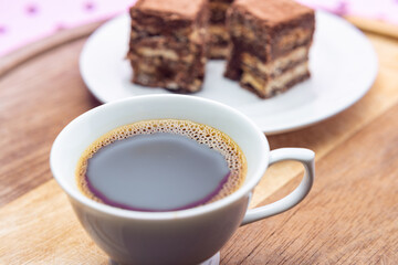 Uma xícara com café e palha italiana sobre madeira, sobre superfície cor-de-rosa. 