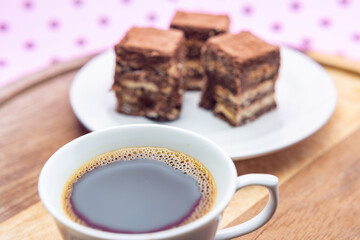 Uma xícara com café e palha italiana sobre madeira, sobre superfície cor-de-rosa. 