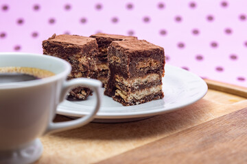 Uma xícara com café e palha italiana sobre madeira, sobre superfície cor-de-rosa. 