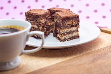 Uma xícara com café e palha italiana sobre madeira, sobre superfície cor-de-rosa. 