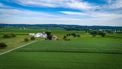 Naklejka premium Aerial View of Farmlands With Barns and Silos, Looking Over the Hills and Fields of Rich Crops Growing on a Sunny Summer Day