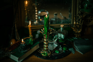Fototapeta na wymiar Illustration of magical stuff....candle light, Chrystal ball, magic wand, book of spells dark background, Slytherin school, green aesthetic, Halloween time