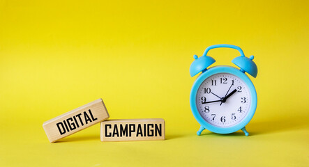The digital campaign is written on wooden blocks and a yellow background with a clock. Internet business marketing concept