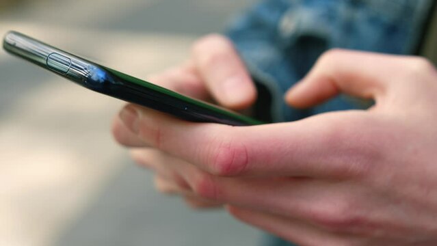 Extreme close-up hands of unrecognizable man typing online message using mobile phone 