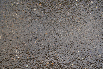 Wet coarse asphalt of a coarse grain road photographed from above