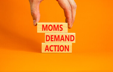 Moms demand action symbol. Concept words Moms demand action on wooden blocks on a beautiful orange...