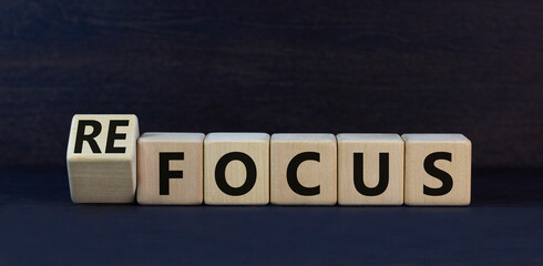 Focus or refocus symbol. Turned wooden cubes and changed the concept word focus to refocus. Beautiful black table black background. Business focus or refocus concept. Copy space.