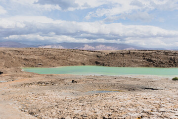 Sinkhole filled with turquoise water, near Dead Sea coastline. Hole formed when underground salt is dissolved by freshwater intrusion, due to continuing sea-level drop. . High quality photo