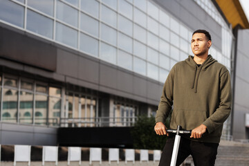 young african american man in casual clothing posing on electric scooter.