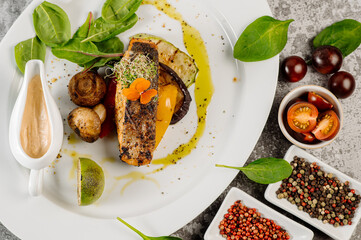 Grilled salmon fish steak with mushrooms and herbs on grey concrete background