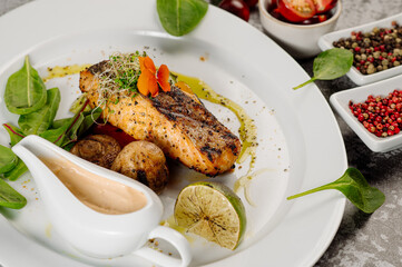 Grilled salmon fish steak with mushrooms and herbs on grey concrete background