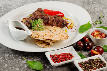 Grilled meat kebab with pita and vegetables on concrete background
