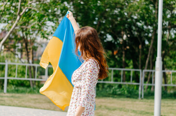 Girl with the flag of Ukraine. Ukrainian woman with the flag of Ukraine. Flag of Ukraine. Patriotic photo of a Ukrainian woman with the flag of Ukraine