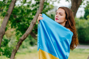 Girl with the flag of Ukraine. Ukrainian woman with the flag of Ukraine. Flag of Ukraine. Patriotic photo of a Ukrainian woman with the flag of Ukraine