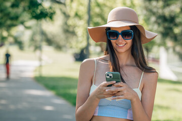 girl in summer with mobile phone and sunglasses on the street