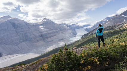 Fototapeta na wymiar Male hiker overlooking untouched alpine valley with glacier on its end, Jasper, Canada